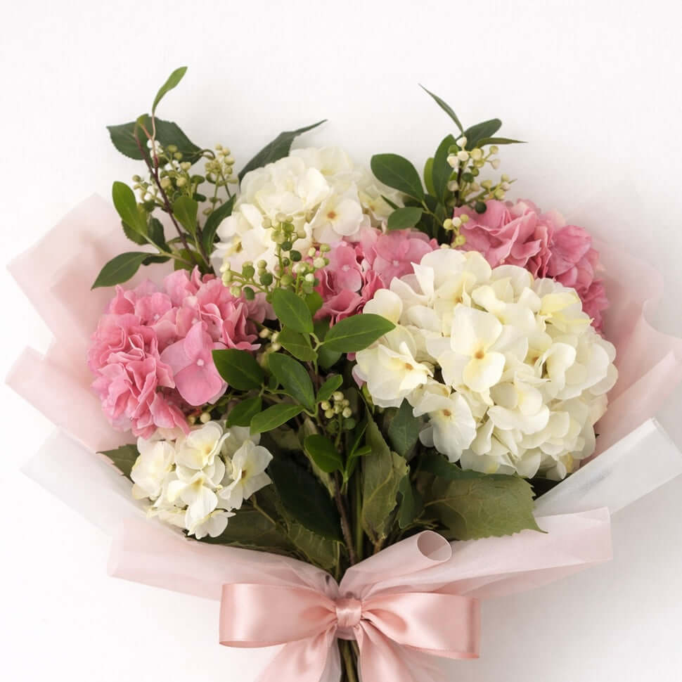Bouquet of pink and white flowers with a pink ribbon on a white background