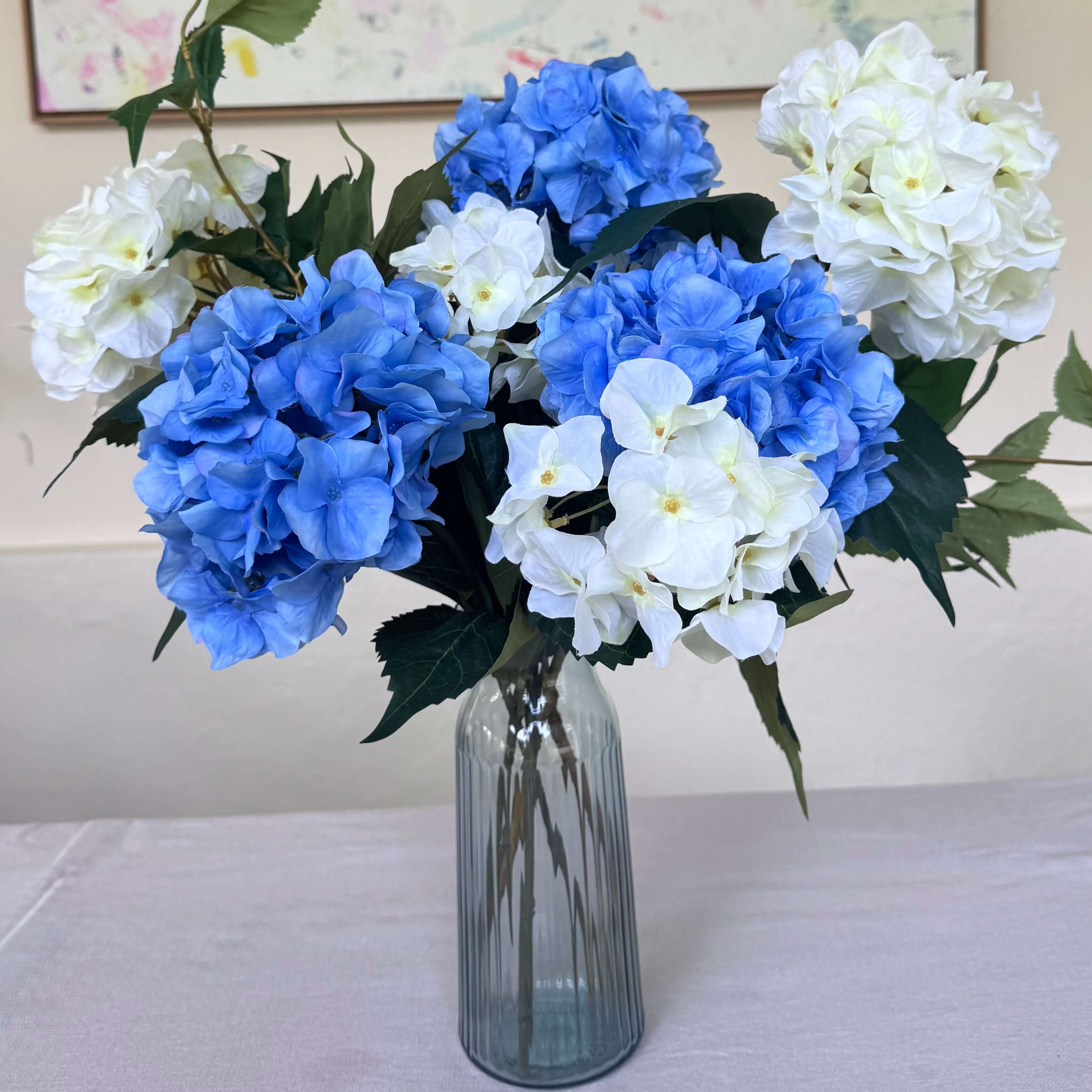 Blue and purple silk flower arrangement in a glass vase