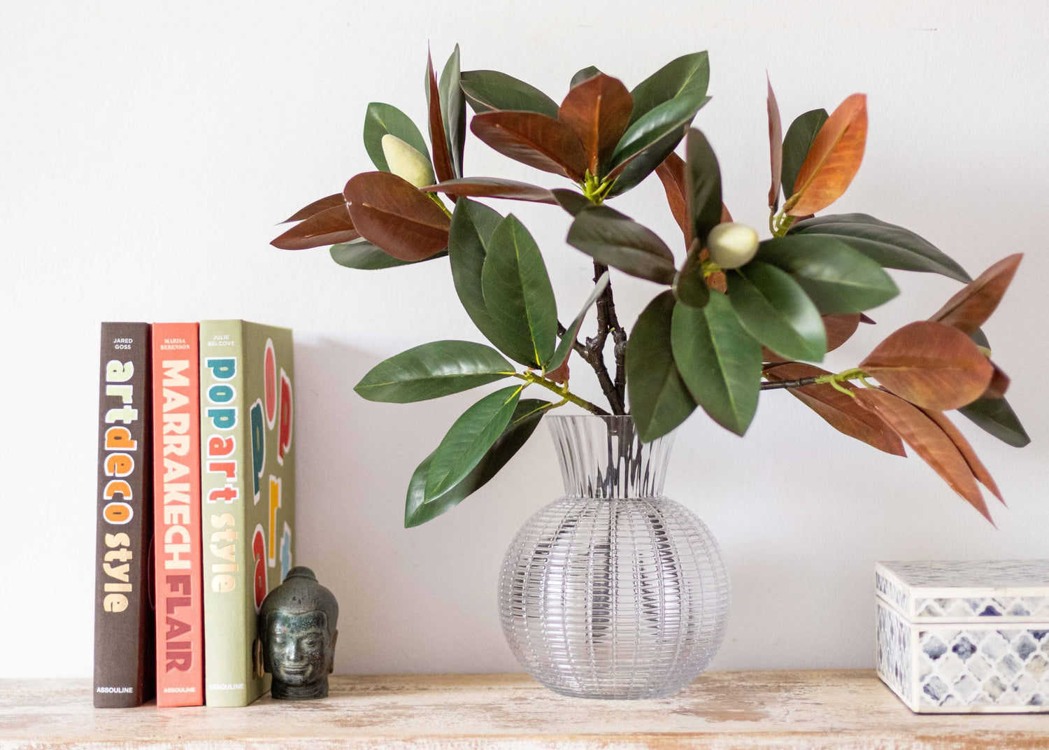 faux magnolia stems in glass vase