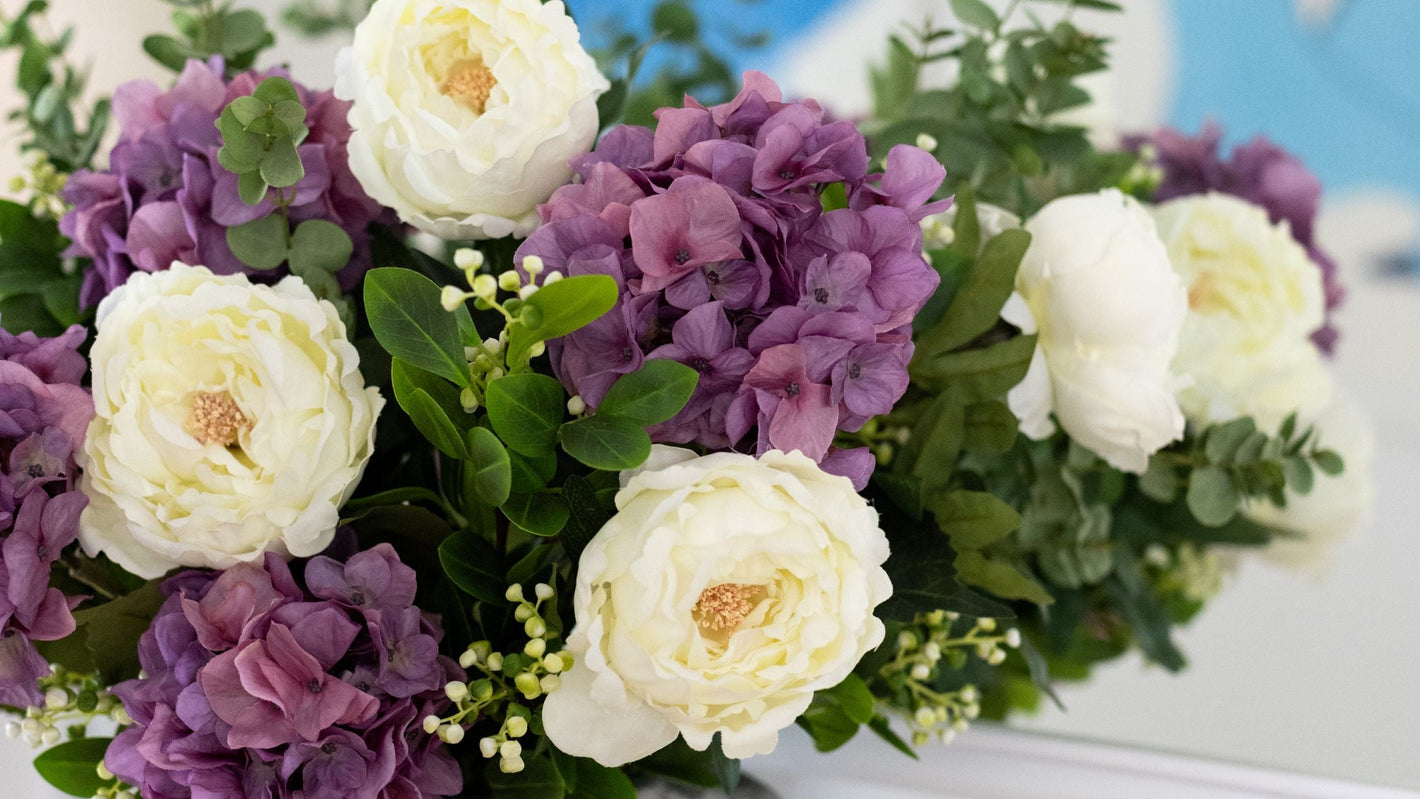 Bouquet of purple and white flowers in a gray vase.